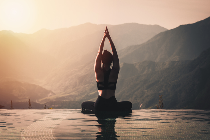 Beautiful Attractive Asian woman practice yoga Lotus pose on the pool above the Mountain peak in the morning in front of beautiful nature views,Feel so comfortable and relax in holiday,Warm tone